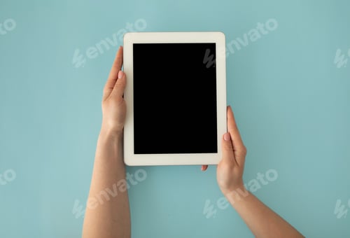 Preview: Female hands holding digital tablet computer with mockup for your design on blank screen on blue