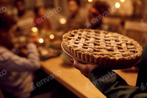 Preview: Close up of woman serving pie to her family during Thanksgiving lunch in dining room.