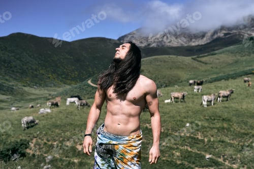 Preview: young caucasian man with long loose hair, naked torso with a pareo around his waist, eyes closed