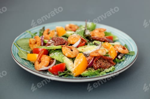Preview: A plate of salad with shrimp, arugula and other vegetables, one plate on a gray table