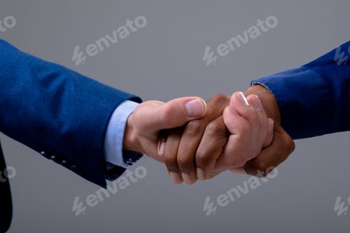 Preview: Caucasian and african american business people shaking hands, isolated on grey background