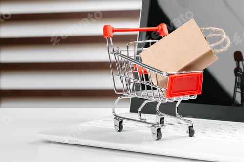 Preview: Online shopping concept. Shopping cart, laptop on the desk