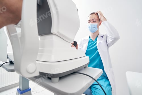 Preview: Male doctor looking at the refraction machine