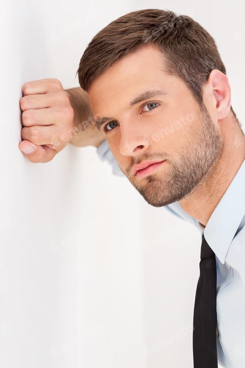 Preview: Confident and inspired. Handsome young man in shirt and tie leaning at the wall and looking away