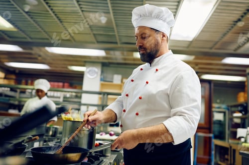 Preview: Professional mature chef cooking in a restaurant.