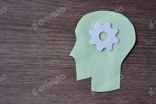 Preview: A green paper cut-out of a human head with a white gear in the center of the head.