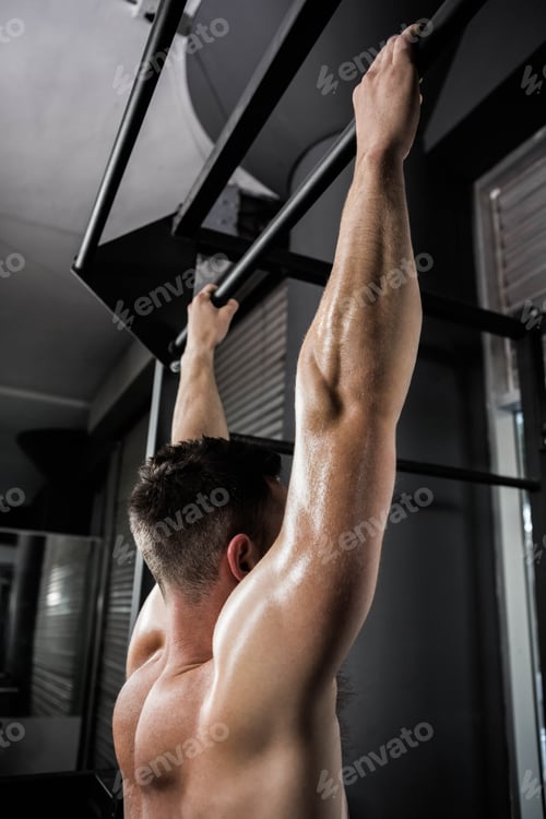 Preview: Shirtless man doing pull up at the crossfit gym