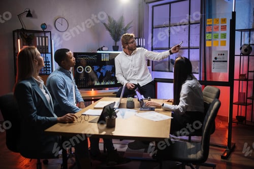 Preview: Man showing financial statistic to diverse partners