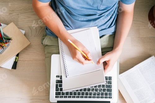 Preview: Teen boy lies on the floor in front of a laptop. Classes at home. Remote training.