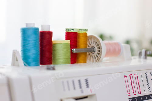 Preview: Closeup colorful thread spools on sewing machine.