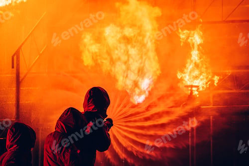 Preview: Fearless Firefighters Battling Blaze with Water and Extinguishers.