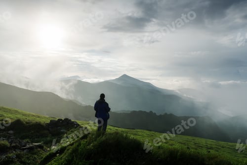 Preview: Man silhouette on cloudy mountains