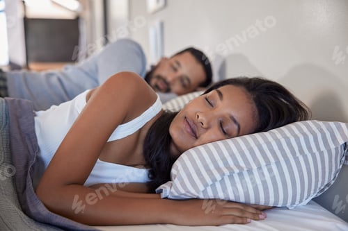 Preview: Indian couple with closed eyes sleeping in bed together
