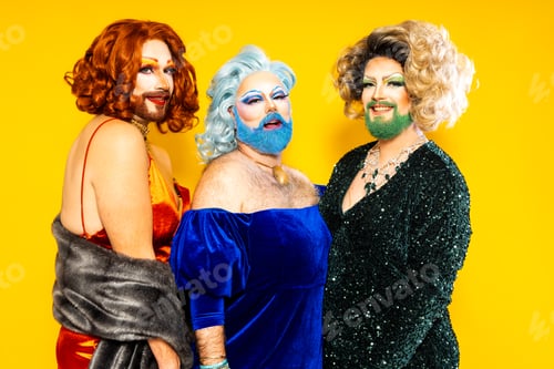 Preview: Three happy drag queens standing together againts yellow background