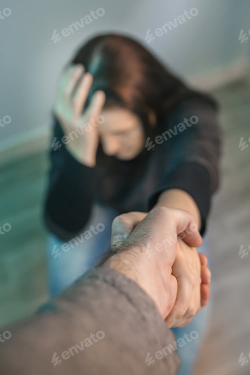 Preview: Unrecognizable woman with mental disorder receiving help from man holding her hand