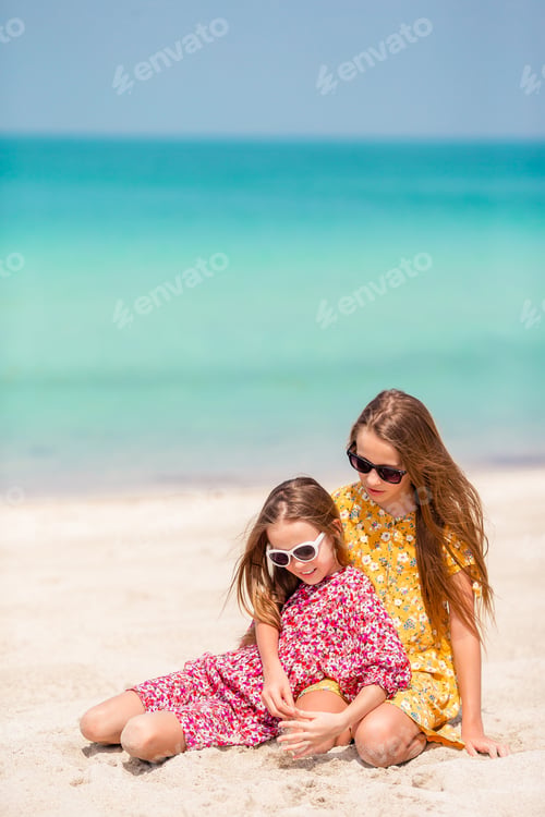 Preview: Little happy funny girls have a lot of fun at tropical beach playing together