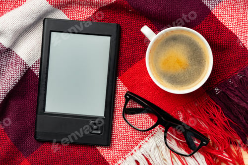 Preview: E-book reader and cup of coffee on knit plaid background