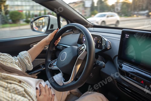 Preview: A pregnant young woman is driving a car. Hands on the wheel.