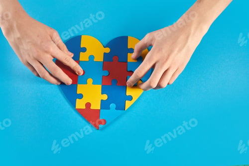 Preview: Autistic boy hands holding jigsaw puzzle heart shape. World Autism Awareness Day