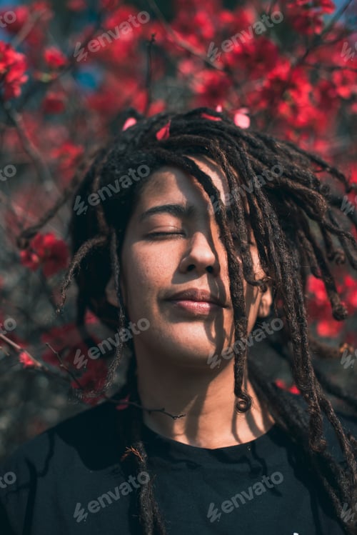 Preview: Close up portrait of woman with eyes closed standing against blooming flowers