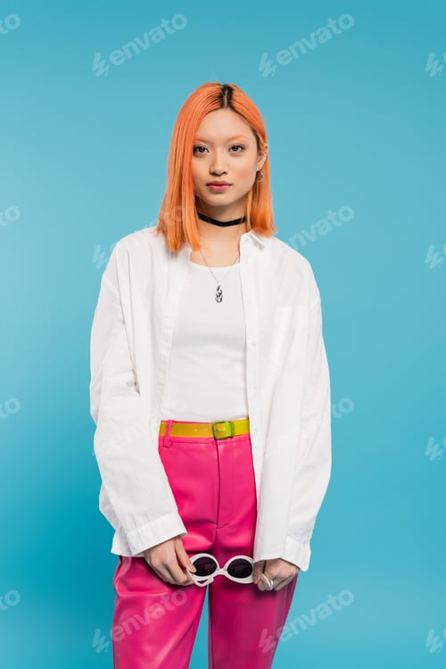 Preview: young asian fashion model in white shirt, pink pants and trendy accessories holding sunglasses and