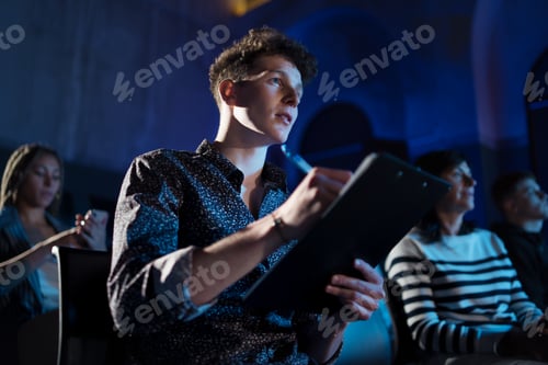Preview: Group of people making notes while listening to presentation at conference