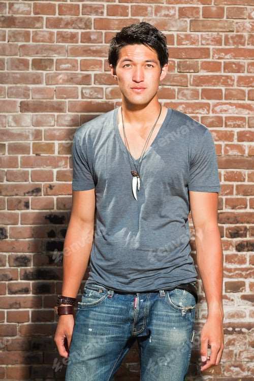 Preview: Urban Asian Man. Good Looking. Cool Guy. Wearing Grey Shirt And Jeans. Standing In Front Of Brick