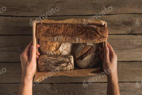 Preview: cropped shot of human hands holding box with assorted homemade bread