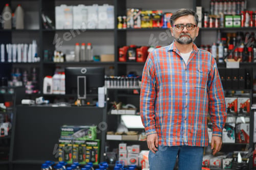 Preview: Salesman standing in auto parts store with shelves full of products