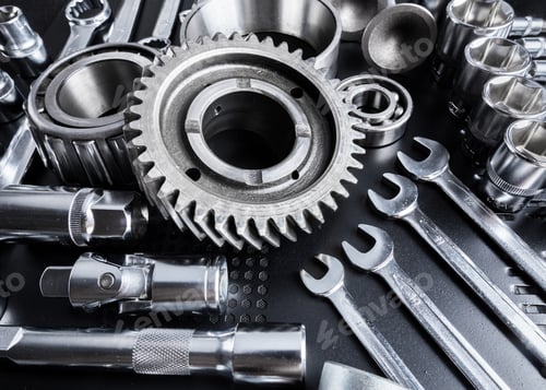 Preview: Collection of metal tools and mechanical parts on a dark surface during a workshop session