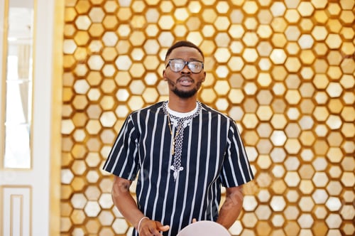 Preview: Attractive mature african american man in stylish clothing posing next to the golden wall.