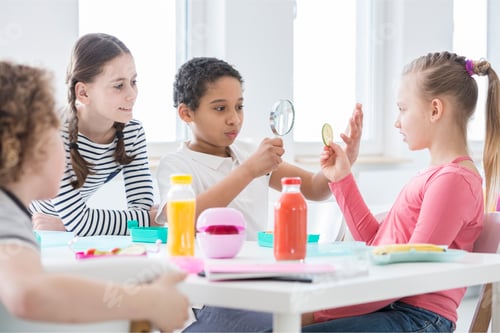 Preview: A young boy looking through a magnifying glass and a girl holdin