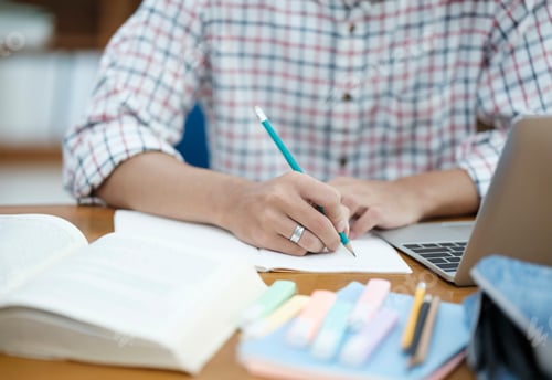 Preview: Student Taking Notes in Library with Laptop