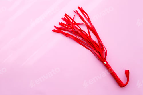 Preview: Leather red whip on a pink background. Sex toy. Flat lay.