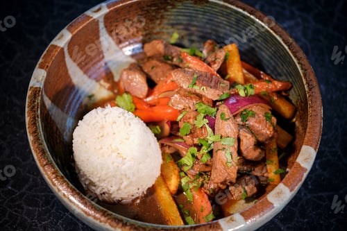 Preview: Bowl with delicious fried beef with vegetables and rice on black table