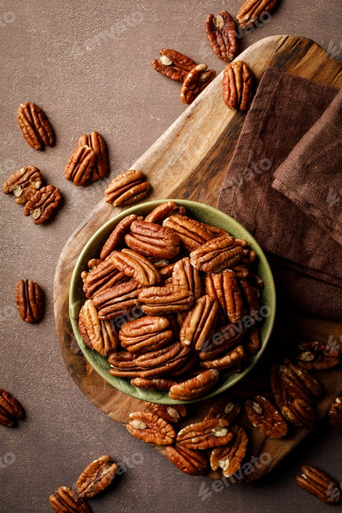 Preview: Pecan nuts in a bowl on a brown background, top view