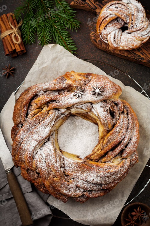 Preview: Christmas pie roll with cinnamon and powdered sugar on a dark old concrete or stone background. Sele