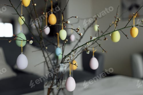 Preview: Tree branches decorated with colored easter eggs at home in modern apartment