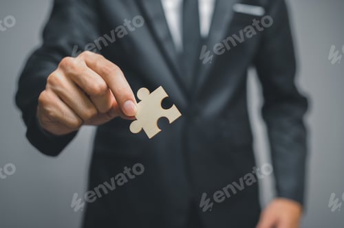 Preview: Concept of finding new solutions in a business, closeup of a man in a suit holding a jigsaw puzzle