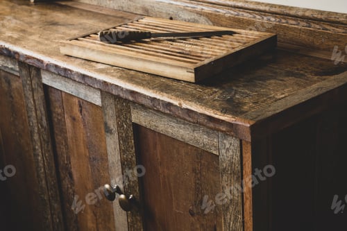 Preview: High angle close up of wooden chopping board and knife on vintage wooden kitchen cupboard.