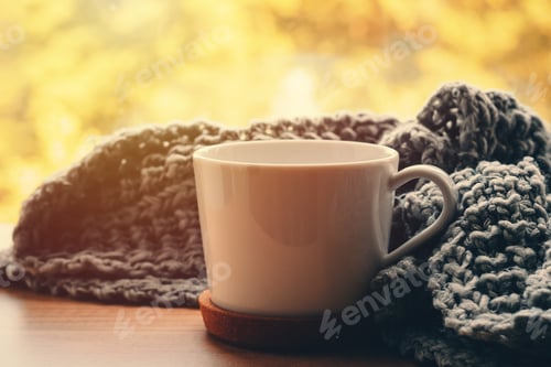 Preview: Cozy home at autumn day. Woolen scarf and cup of tea on the windowsill