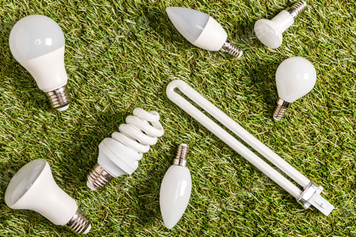 Preview: top view of fluorescent lamps on green grass, energy efficiency concept