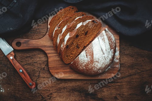 Preview: Rye sourdough bread with raisins, sliced pieces on wooden cutting board, bread knife