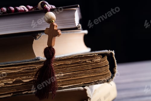 Preview: Close-up wooden cross and old books stack.