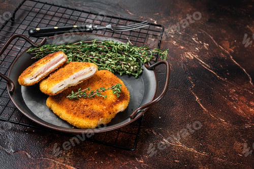 Preview: Cordon bleu chicken fillet cutlet with ham and cheese. Dark background. Top view. Copy space