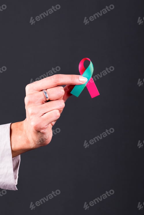 Preview: Woman’s hand holding a pink and teal ribbon, symbol of Hereditary and gynecologic cancers