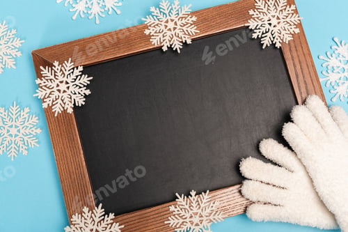 Preview: top view of winter white gloves, chalkboard and snowflakes on blue background