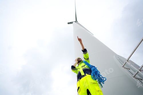 Preview: Windturbine inspector wearing Personal protective equipment working at wind turbines farm .