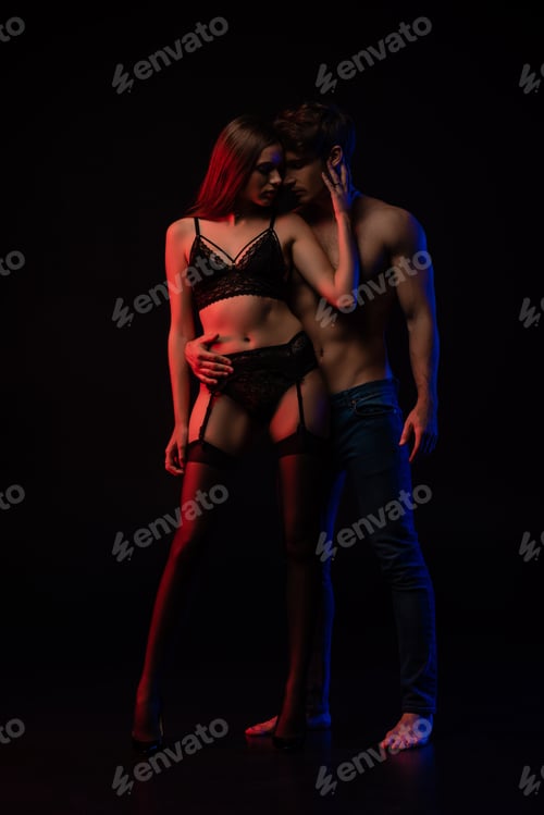 Preview: undressed sexy young couple hugging in red light isolated on black