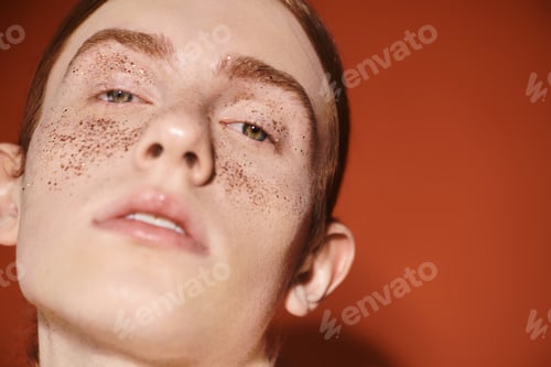 Preview: Stylish young queer man with striking features posing against a vibrant backdrop